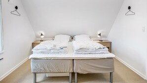 A bedroom with a bed, bedside lamps, and a hanging light fixture.