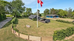 A flagpole with a flag, a covered outdoor seating area, and a building with a blue roof. - "Herbert" - 1km from the sea by Interhome (Humble)