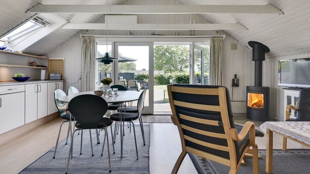 A modern kitchen with white cabinets, a dining area with a table and chairs, and a wood-burning stove. - "Herbert" - 1km from the sea by Interhome (Humble)