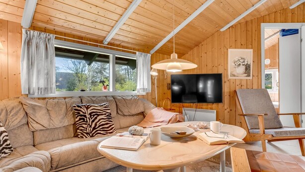 Ein gemütliches Wohnzimmer mit einer Couch, einem Couchtisch, einem Fernseher und einem Sessel.