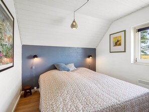 A bedroom with a bed, two wall-mounted lamps, a small stool, and a window with a view. - "Taralyn" - 1.3km from the sea by Interhome (Væggerløse)