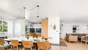 A modern kitchen with white cabinets, a dining area with wooden chairs, and a living room with a sofa and a TV. - "Taralyn" - 1.3km from the sea by Interhome (Væggerløse)