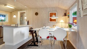 Une cuisine moderne avec des meubles blancs, un îlot central et un coin repas avec des chaises blanches.
