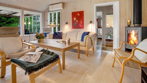 Un salon confortable avec un canapé, une table basse et des fauteuils, une cheminée et de grandes fenêtres.