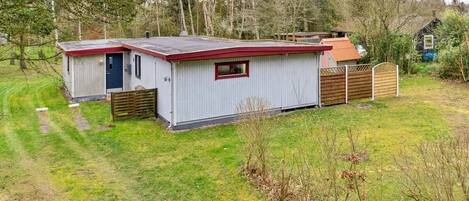 Un petit bâtiment métallique d’un seul étage, avec un toit rouge, une porte et une fenêtre.
