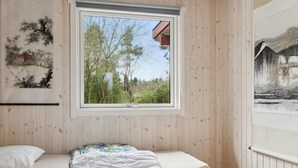 Une pièce avec un lit, une fenêtre et des murs en bois.