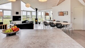 A spacious living area with a large window, a fireplace, and a dining table with chairs. - "Luzia" - 1.2km from the sea by Interhome (Ringkøbing)