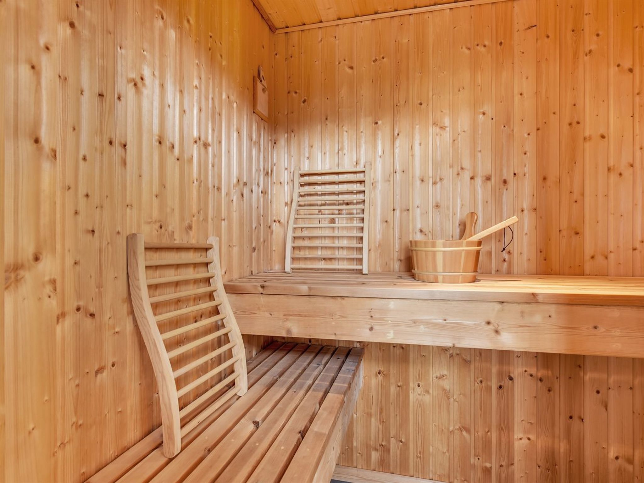 Un sauna en bois avec des bancs et un seau en bois.