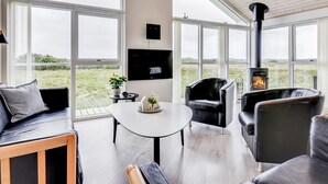 A modern living room with a fireplace, large windows, and a flat-screen TV. - "Luzia" - 1.2km from the sea by Interhome (Ringkøbing)