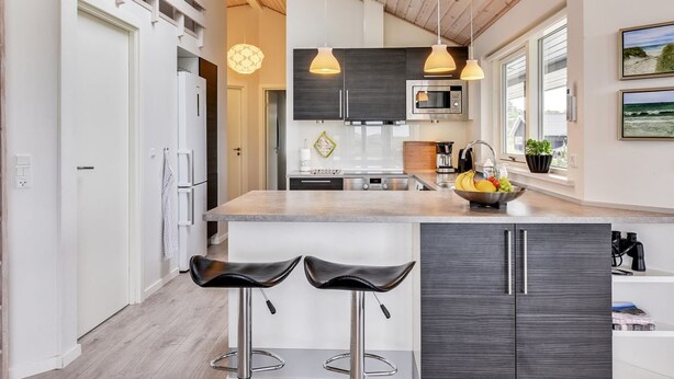 A modern kitchen with a central island, two bar stools, pendant lighting, and a view of the ocean through large windows. - "Luzia" - 1.2km from the sea by Interhome (Ringkøbing)