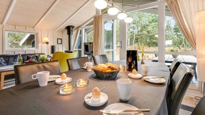A dining area with a table set for breakfast, a fireplace, and large windows offering a view of the outdoors. - "Abiorn" - 2.5km from the sea by Interhome (Blåvand)