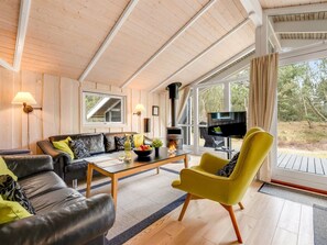 A modern living room with a sofa, armchair, coffee table, TV, fireplace, and large windows. - "Abiorn" - 2.5km from the sea by Interhome (Blåvand)