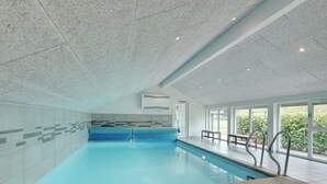 Ein Innenpool mit klarem, blauem Wasser, gefliesten Wänden und einer Decke mit einem gesprenkelten Muster.