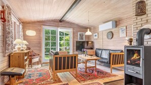 Ein gemütliches Wohnzimmer mit Kamin, Holzwänden, einer Couch, einem Couchtisch und einem Fernseher.