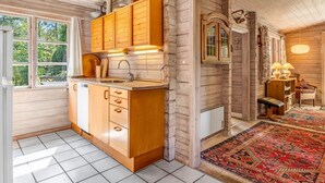 Ein Holzhütten-Innenraum mit einer Küche, die Holzschränke, ein Waschbecken und ein Fenster mit Vorhängen zeigt.