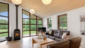 A spacious living room with a fireplace, large windows, a leather sofa, and a coffee table.