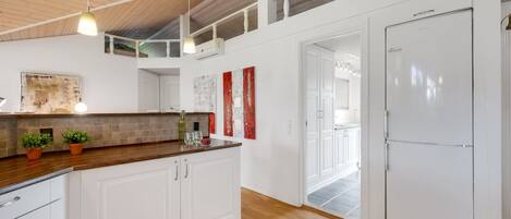 A modern kitchen with wooden flooring, white cabinetry, and a large island.