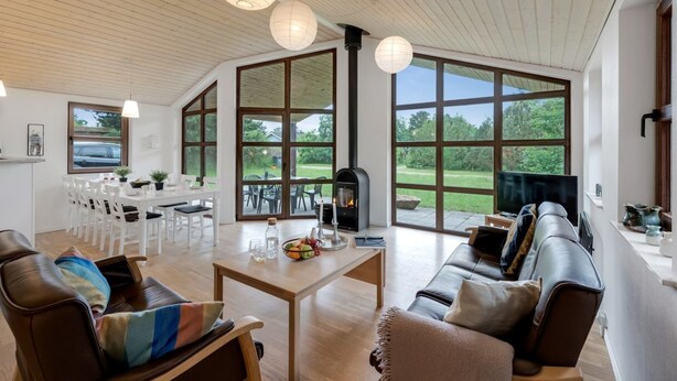 A spacious living area with a fireplace, large windows, and a dining area with white furniture.