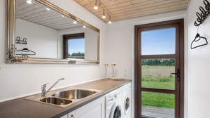 A compact kitchen with a sink, a washing machine, and a large mirror.