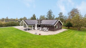 A two-story house with a covered patio area, solar panels on the roof, and a well-maintained lawn. - "Enid" - 700m from the sea by Interhome (Væggerløse)