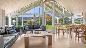 A spacious living area with a modern design, featuring a leather sofa, wooden coffee table, and a dining set. - "Enid" - 700m from the sea by Interhome (Væggerløse)