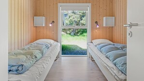 A bedroom with two beds, wooden walls, a large window, and bedside lamps. - "Dagny" - 300m from the sea by Interhome (Fanø)