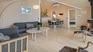 A modern interior with a sofa, coffee table, dining area, and a fireplace. - "Dagny" - 300m from the sea by Interhome (Fanø)