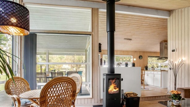 A modern interior with a wood-burning stove, wicker furniture, and a view to the outside. - "Fatlinda" - 1km from the sea by Interhome (Væggerløse)