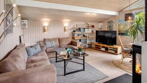 A cozy living room with a sectional sofa, a coffee table, a TV, and a fireplace. - "Fatlinda" - 1km from the sea by Interhome (Væggerløse)