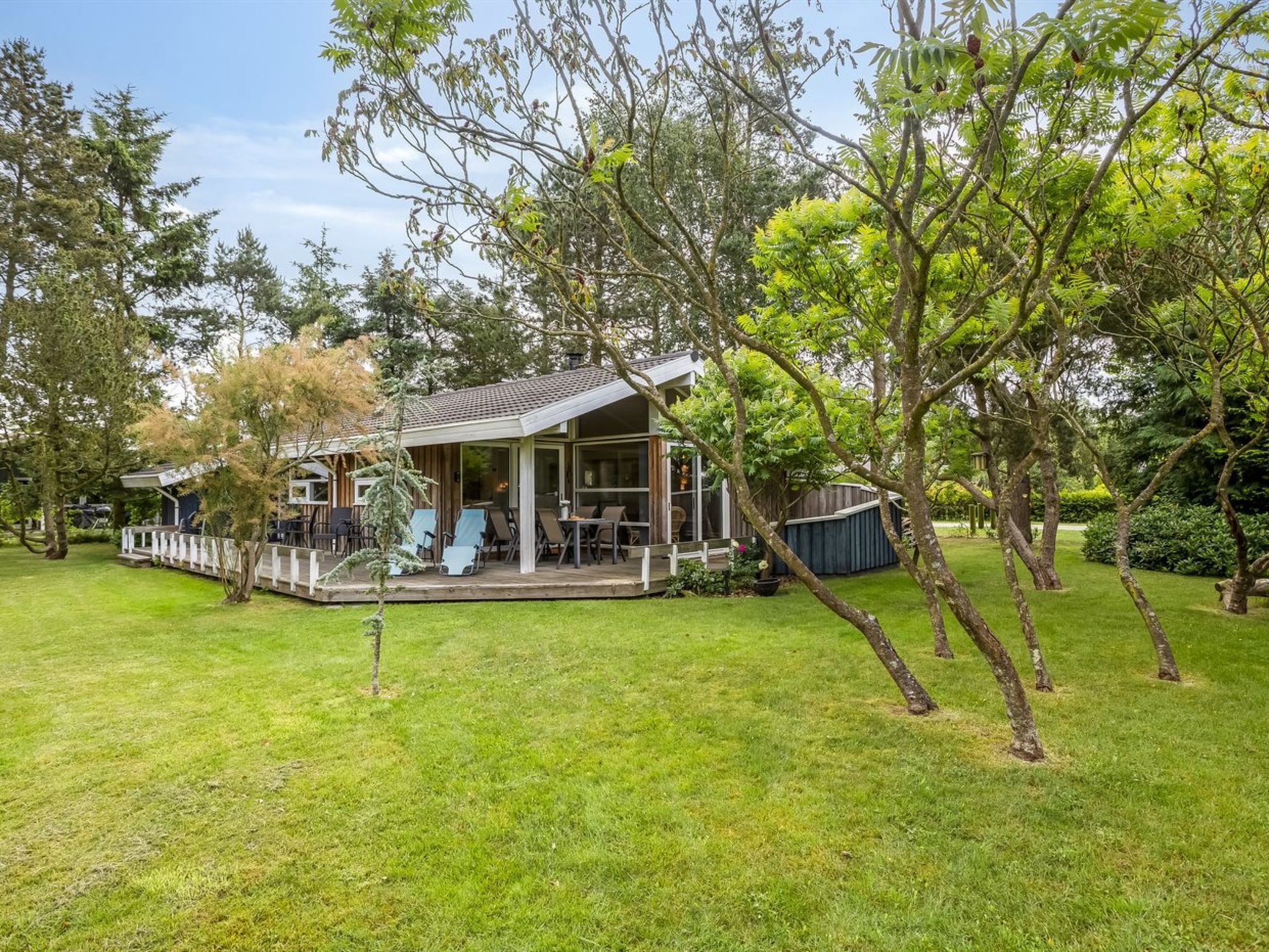 Un accogliente chalet con veranda, immerso nel verde e circondato da alberi.