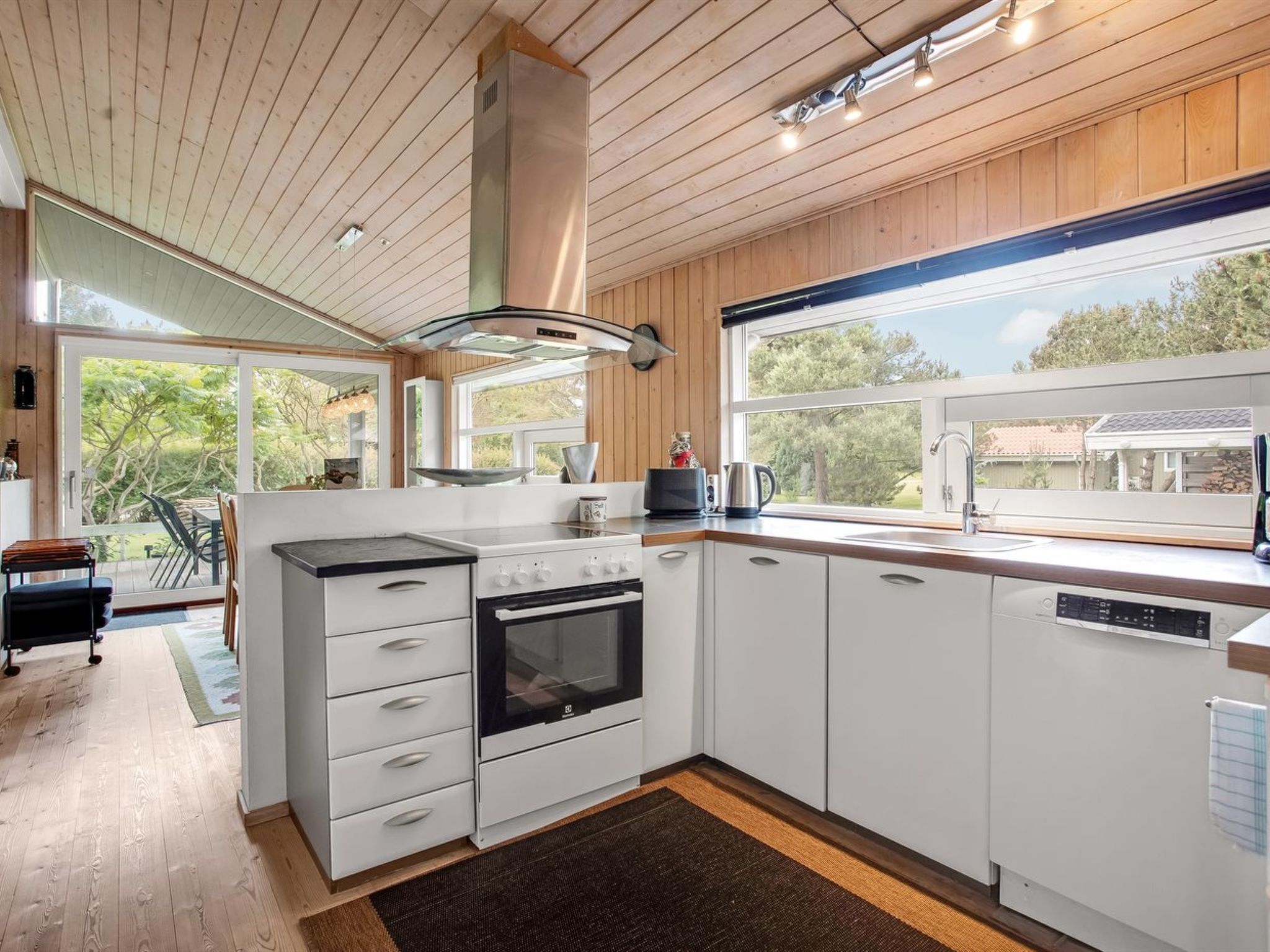 A modern kitchen with white cabinetry, a built-in oven, and a large window offering a view of the outdoors.