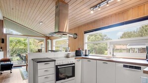 A modern kitchen with white cabinetry, a built-in oven, and a large window offering a view of the outdoors. - "Fatlinda" - 1km from the sea by Interhome (Væggerløse)