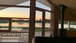 Une pièce dotée de grandes fenêtres donnant sur un plan d’eau et d’une terrasse.