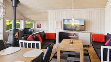 A cozy living room with a fireplace, comfortable seating, a television, and a dining area.