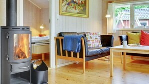 A cozy room with a wood-burning stove, a sofa with colorful cushions, a wooden table, and a painting on the wall. - "Lyra" - 800m from the sea by Interhome (Væggerløse)