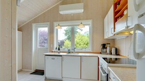 A modern kitchen with white cabinets, a large window, and a wooden ceiling. - "Lyra" - 800m from the sea by Interhome (Væggerløse)