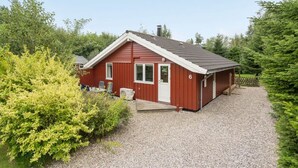 A red single-story house with a gravel driveway, surrounded by greenery. - "Lyra" - 800m from the sea by Interhome (Væggerløse)
