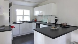 A modern kitchen with white cabinets, a black countertop, and a window providing natural light. - "Borica" - 100m from the sea by Interhome (Væggerløse)