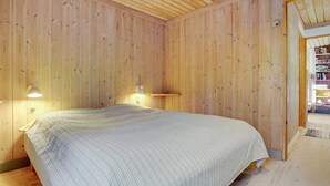 A wooden-paneled room with a bed, two wall-mounted lamps, and a bookshelf. - "Robert" - 250m from the sea by Interhome (Væggerløse)