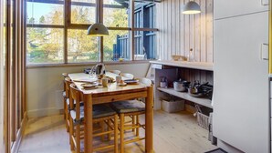 A kitchen with wooden walls, a dining table with chairs, a hanging lamp, and a refrigerator. - "Robert" - 250m from the sea by Interhome (Væggerløse)