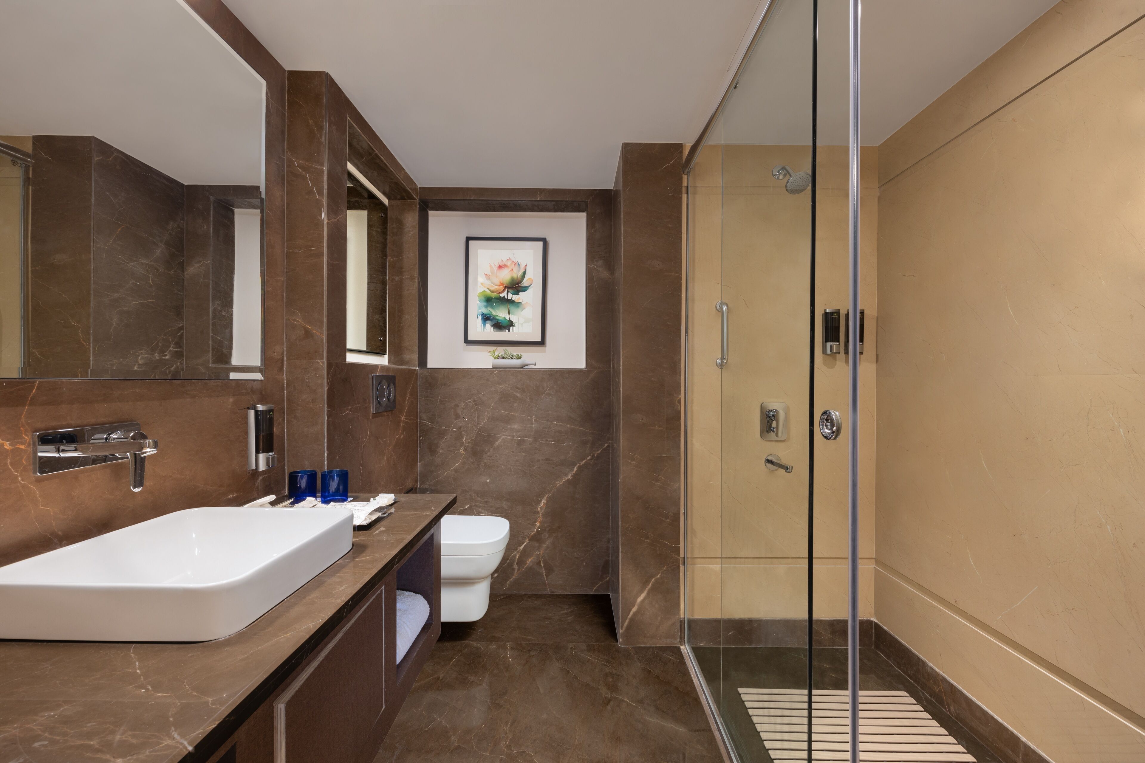 A modern bathroom with a large white sink, a glass shower enclosure, and a marble-tiled floor.