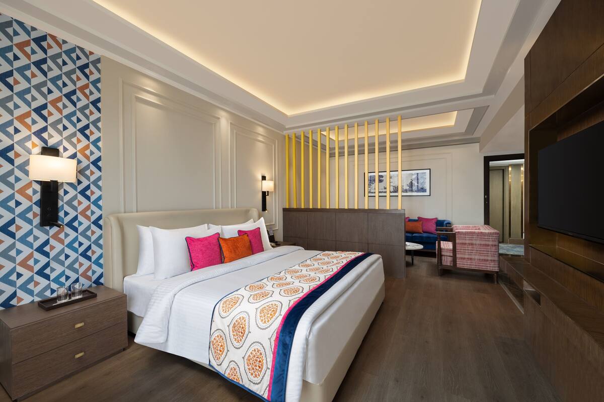 Een moderne hotelkamer met een groot bed, nachtkastjes, een televisie en een behang met een patroon.