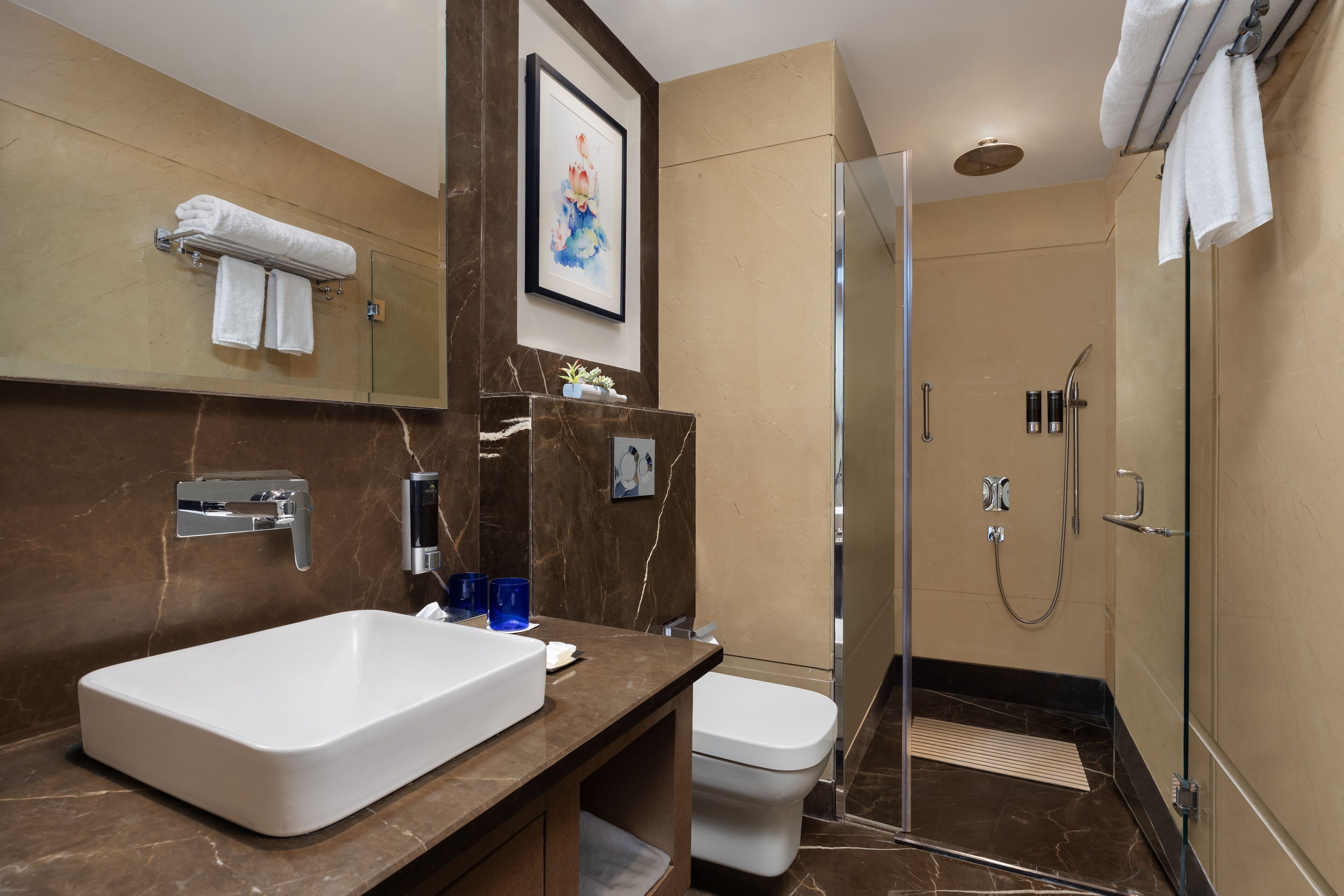 A modern bathroom with a large white sink, a toilet, and a glass-enclosed shower.