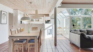 A spacious dining area with a wooden table and chairs, a modern pendant light, and a view of the outdoors through large windows. - "Gertrudis" - 2km to the fjord by Interhome (Frøstrup)