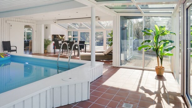 A spacious indoor swimming pool with a glass ceiling, a dining area, and a large potted plant. - "Gertrudis" - 2km to the fjord by Interhome (Frøstrup)