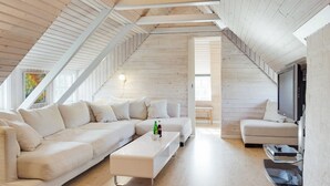 A spacious loft with a high ceiling, wooden beams, a large sectional sofa, a small coffee table, and a television. - "Gertrudis" - 2km to the fjord by Interhome (Frøstrup)