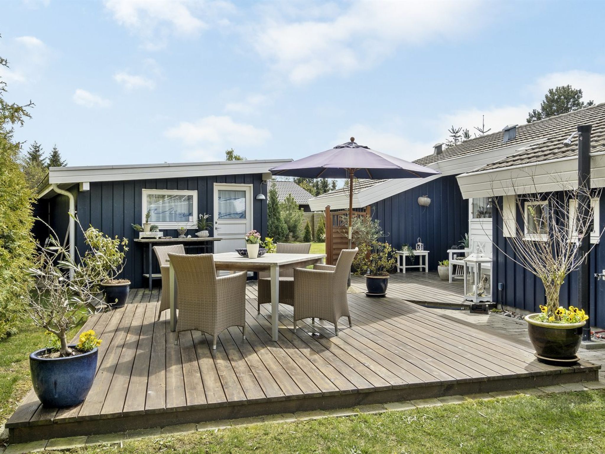 Une terrasse dotée de mobilier d’extérieur, d’un espace barbecue et de plantes en pot.