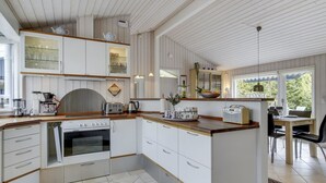 Ett modernt kök med vita skåp, en köksö och en matplats med utsikt.