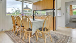 A modern kitchen with wooden cabinets, a built-in oven, and a dining area with a table and chairs.