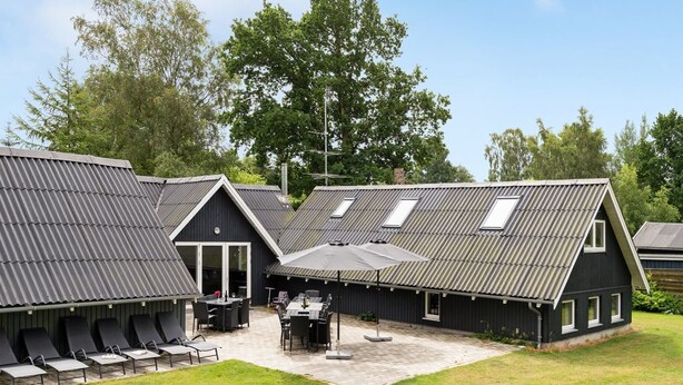 A modern building with a sloped roof, multiple windows, and a patio area with outdoor seating. - "Ingalil" - 650m from the sea by Interhome (Væggerløse)